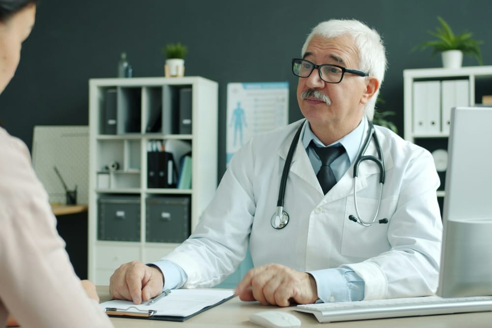An aviation medical examiner discussing a pilot's medical assessment with them at a clinic desk An aviation medical examiner discussing a pilot's medical assessment with them at a clinic desk